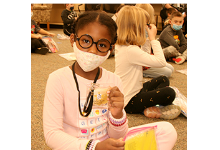 A Glenwood Elementary first-grade girl holds up her Word Detectives badge during a visit with her class to the Super-Secret Detective Agency on December 2, 2021.