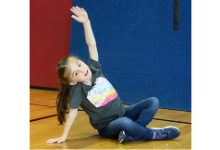 A first-grade Glenwood Elementary student strikes a yoga pose in the gym during Mental Health Awareness Day on May 25, 2023.