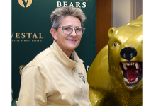 Vestal High School Field Hockey Coach Vickie Sax stands by the Vestal Golden Bear statue.
