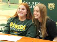Teammates Kay Farro and Shannon Perlungher sit at the signing table together on December 21, 2021.
