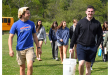 Vestal High School students carry a bucket across a field as they prepare to release baby Brook Trout into Choconut Creek.