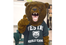 Brown bear mascot wearing green and white Vestal Middle School shirt.