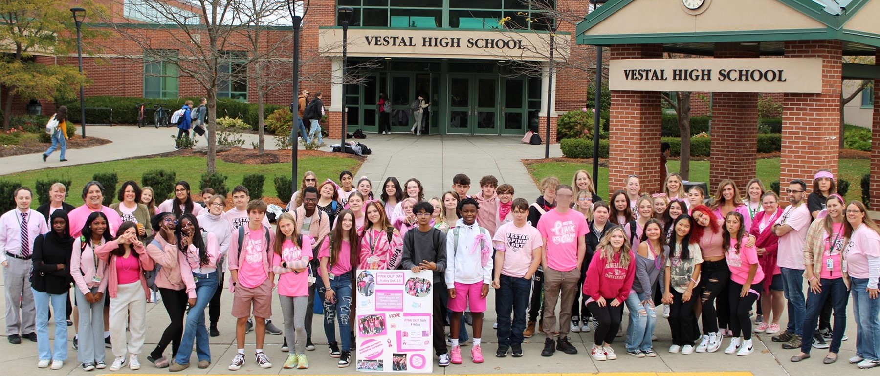 Students dressed in pink stand in front of Vestal High School for the All-Out Pink-Out Day in solidarity with breast cancer survivors.