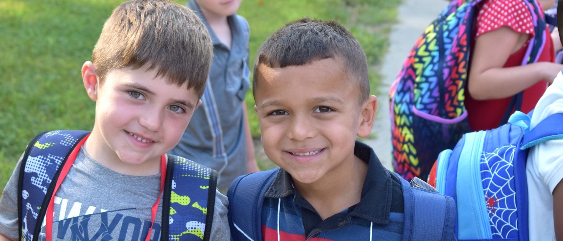 Two Vestal Hills Elementary students smile for the camera after getting off the school bus on the first day of school.