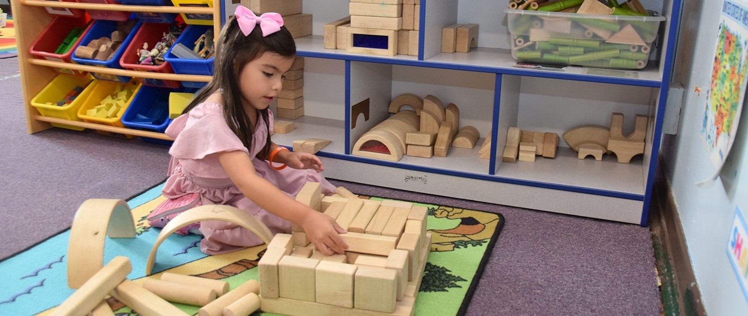 A Universal Pre-Kindergarten student at the Cub Care campus enjoys building with wooden blocks during orientation.