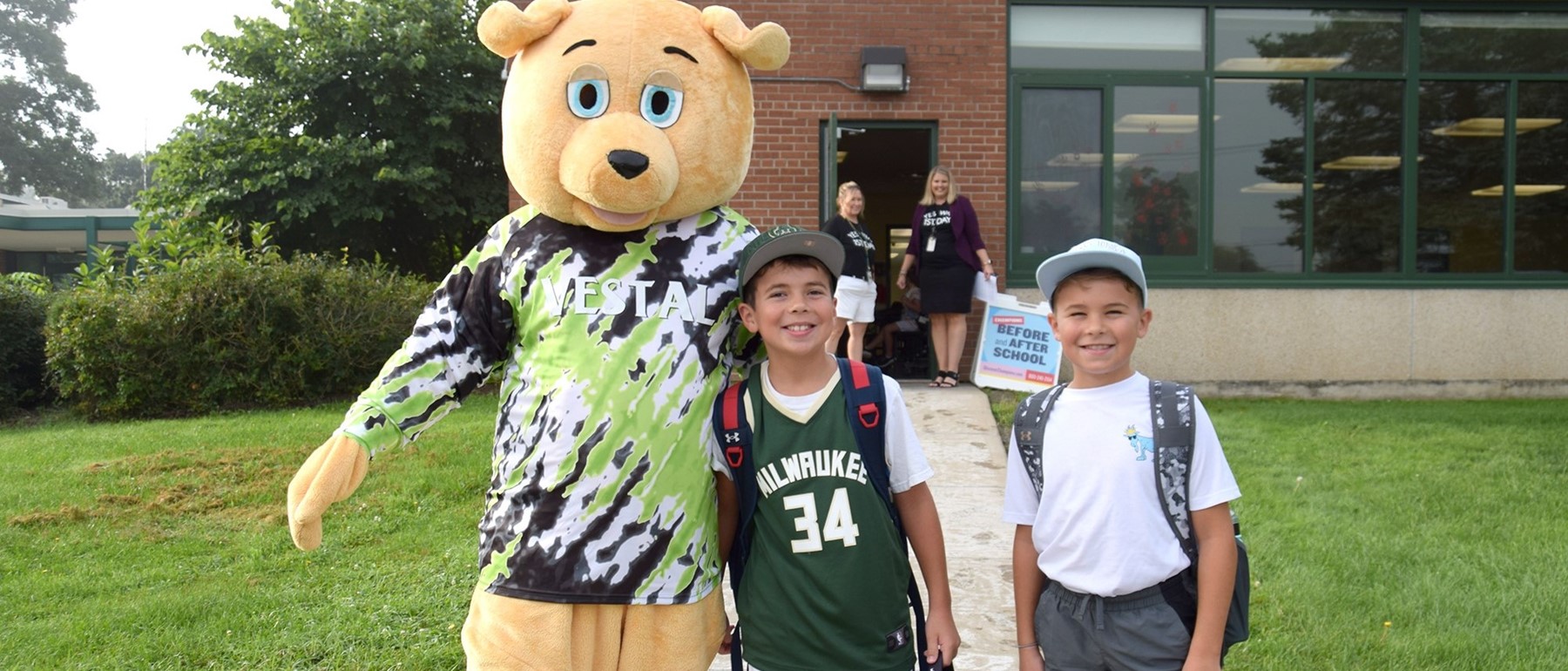 Two brothers are greeted by a tie-dye shirt wearing Vestal bear on the first day of school at Tioga Hills Elementary.