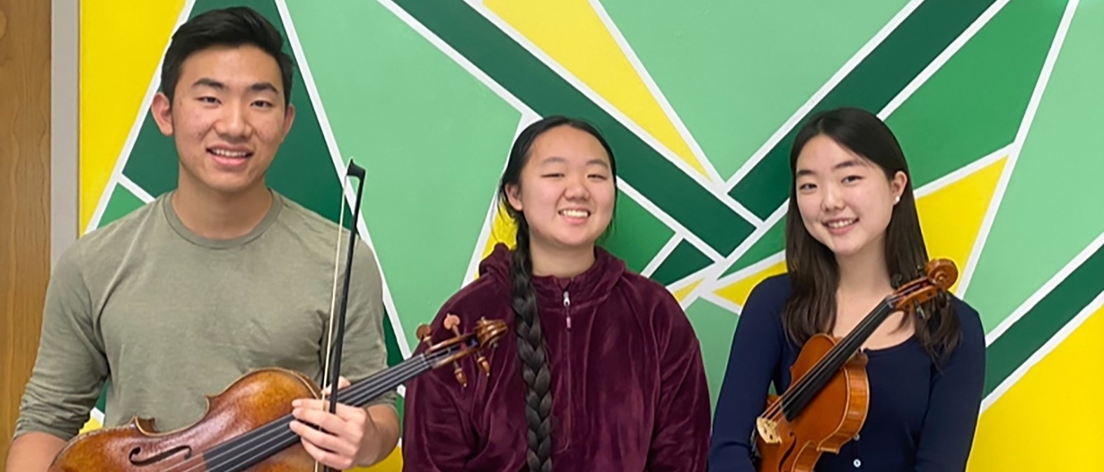 Three Vestal High School musicians who went to the New York State School Music Association Winter Festival stand against a green and yellow wall 