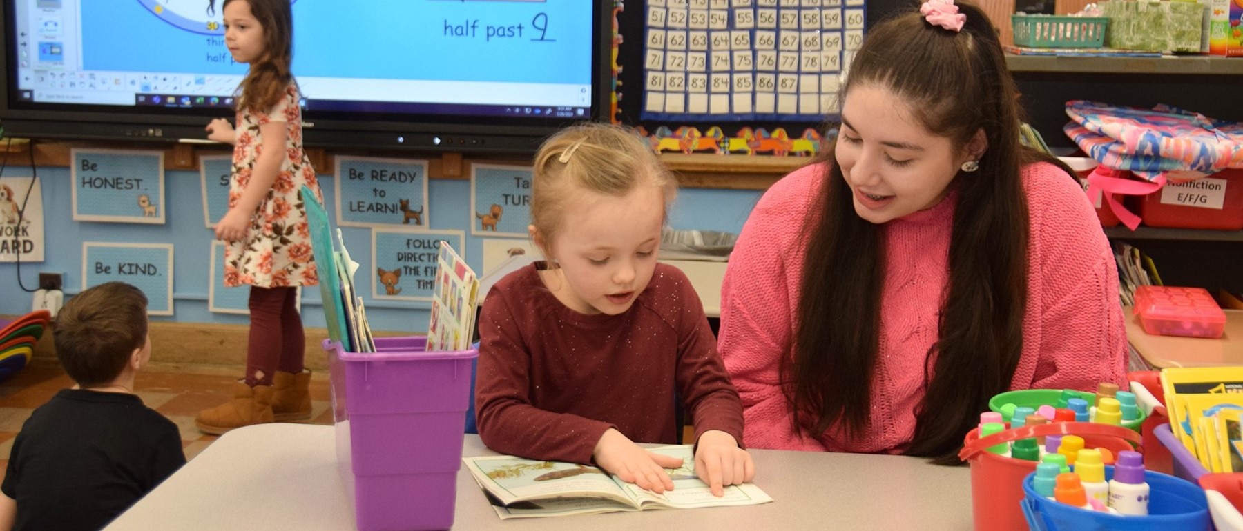 A first-grade girl reads to a visiting ninth-grader during the latter&#39;s Day of Service.