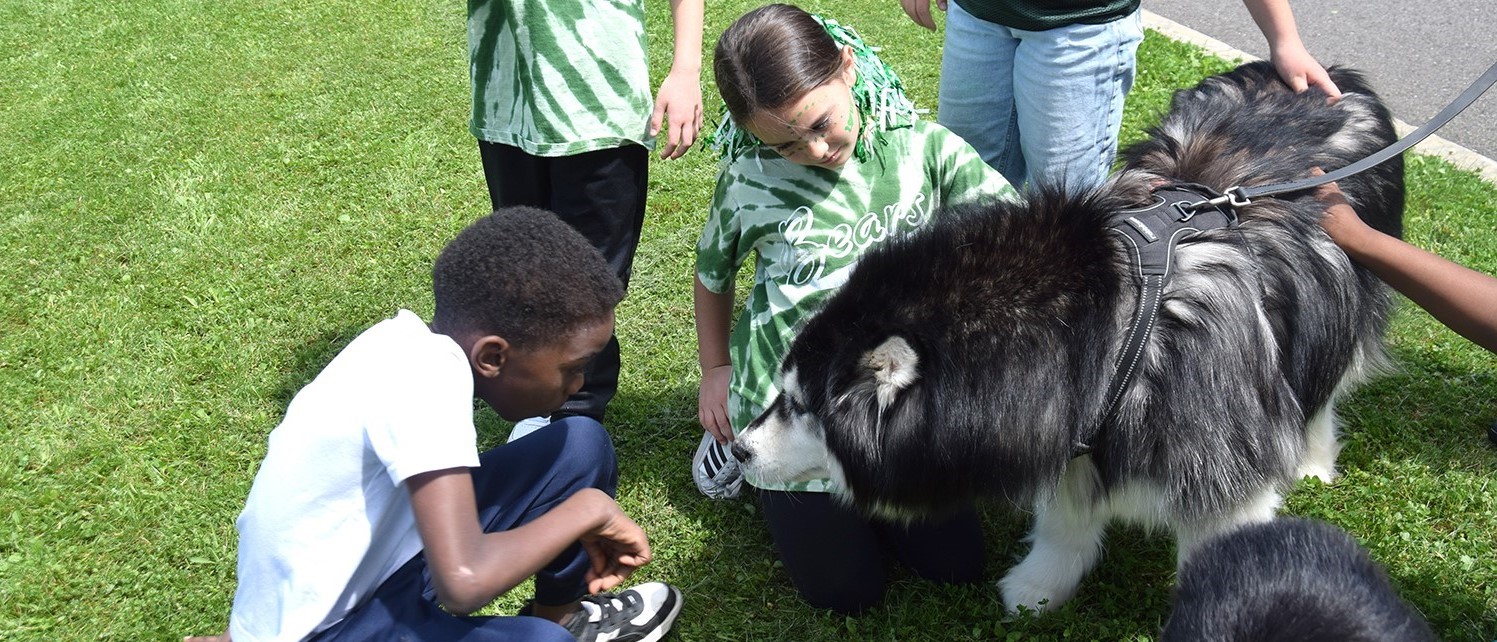 Two African Road Elementary students pet a therapy dog during Mental Health Awareness Day on May 30, 2024.